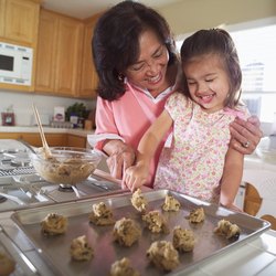 Grandmother helping granddaughter bake cookies