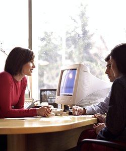 Young couple meeting with woman at desk, side view