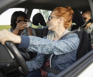Young women friends in car with camera phone, enjoying road trip