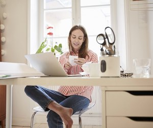 Full length of young woman examining financial bill while working from home