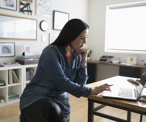 Focused creative businesswoman entrepreneur working at laptop in studio office