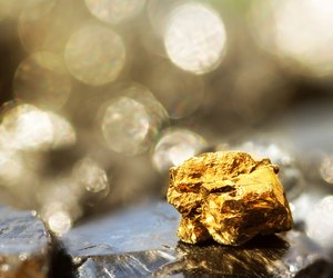 Golden bar on raw coal nuggets with soft focus and shiny background