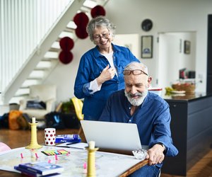 Cheerful retired couple at home planning vacation and man using laptop