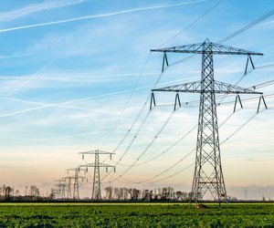 High voltage towers with thick hanging power cables in a rural landscape in the Netherlands