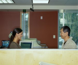 Young bank teller assisting senior customer, side view