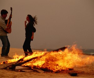 Young couple dancing by campfire at beach