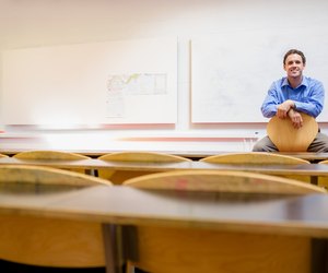 Male teacher sitting on chair in lecture hall