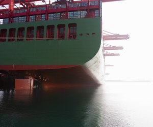 Stern of a green and red docked cargo ship.