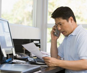Man in home office with computer and paperwork on