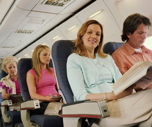 Woman relaxing on plane, smiling, portrait