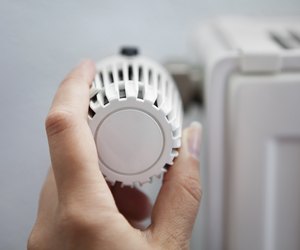 Woman Adjusting The Thermostat