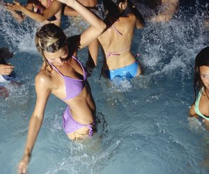 Medium group of young adults dancing in pool at night, elevated view, waist up