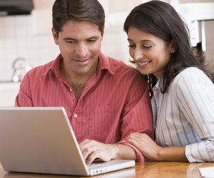 Couple in kitchen with laptop smiling