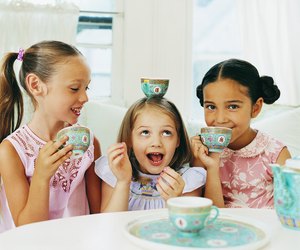 Three Girls Sitting Side by Side Having a Tea Party And Making Fun