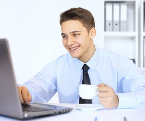 Young smiling businessman with cup of coffee in office