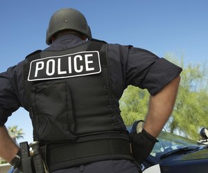 Police officer in bulletproof vest outdoors, back view