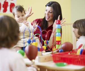 three little girls and female teacher in kindergarten