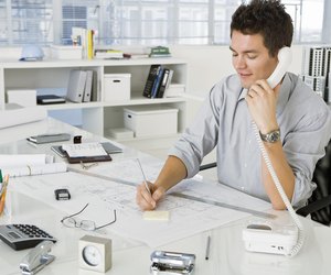 Architect on phone while writing on notepad