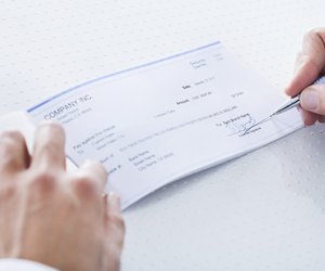 Close-up Of Hand Filling Cheque