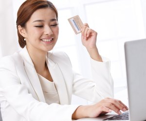 Young business lady holding credit card in front of laptop