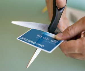 Hands cutting credit card with scissors