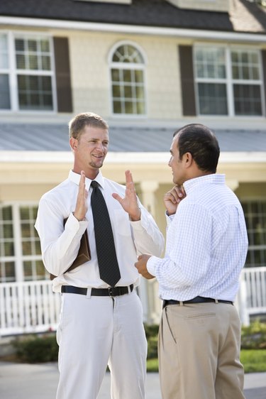 Two men talking in street outside house