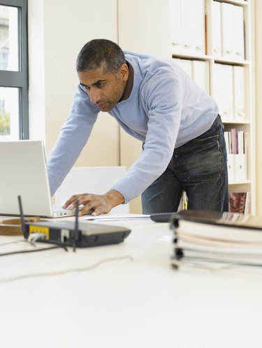 Man standing by desk using laptop computer
