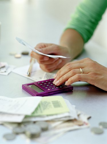 Woman reviewing receipts with calculator, close-up of hands