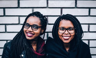 Two cute young Black women in glasses smiling together
