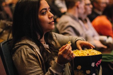 Woman in movie theater holding large bag of popcorn