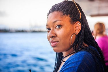 Black woman looking sidelong into camera next to water