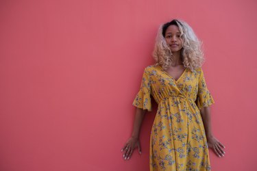 Young Woman of color in yellow dress against raspberry wall