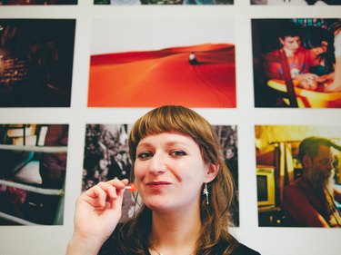 Smiling woman with lollipop in front of photo gallery