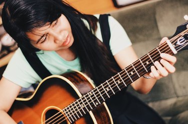 Young woman practices guitar
