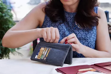Woman going through open wallet to pay check at restaurant