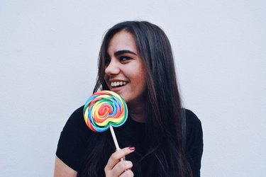 Young woman dressed in black holding rainbow lollipop