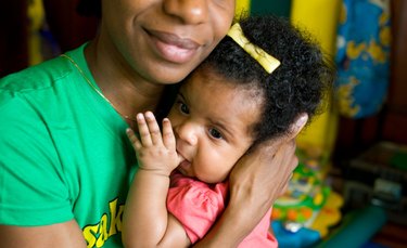 Black mother smiling as she cradles a baby girl