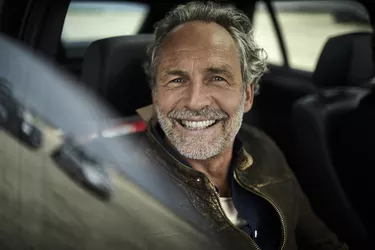 Portait of happy man with grey hair in a car