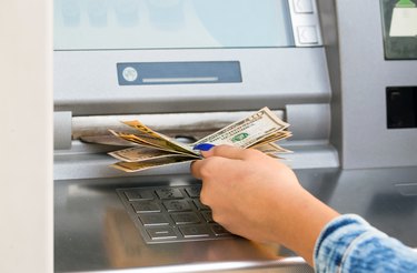 woman hand withdrawing money from outdoor bank ATM