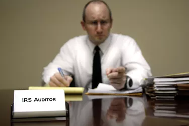 A male IRS tax auditor at a desk with paperwork