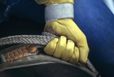 Glove of rodeo cowboy gripping rope