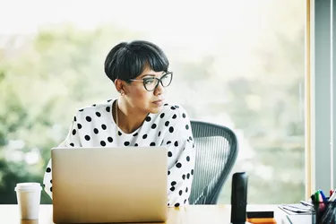 Portrait of mature businesswoman working on laptop at workstation in office