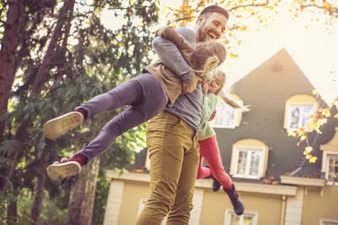 Father carrying daughters around neck.  Side view.