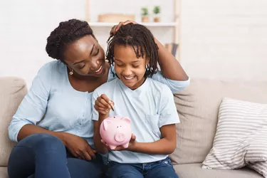 Little girl putting money to piggy bank