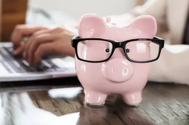 Pink Piggy Bank With Black Eyeglasses On Office Desk
