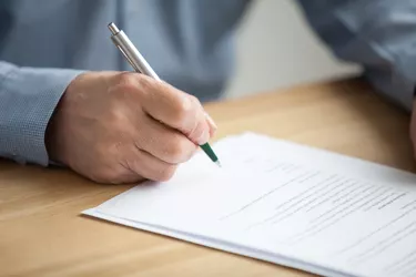 Male hand signing document, senior man putting signature on paper