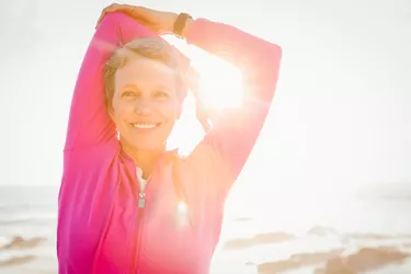 Smiling sporty woman stretching arms at promenade