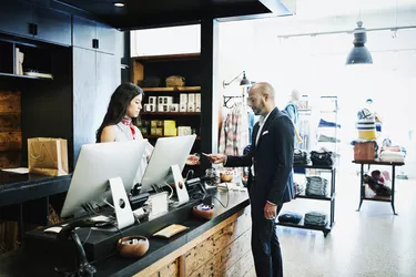 Man handing shopkeeper credit card after shopping in mens boutique