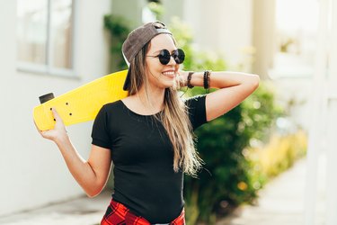 Portrait of smiling young female skateboarder with her skateboard outdoors