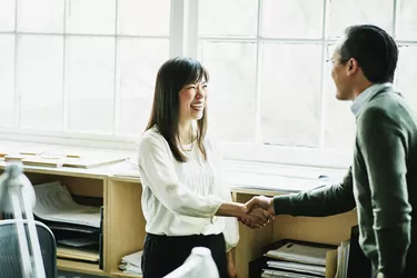 Smiling businesswoman shaking hands with client in design studio
